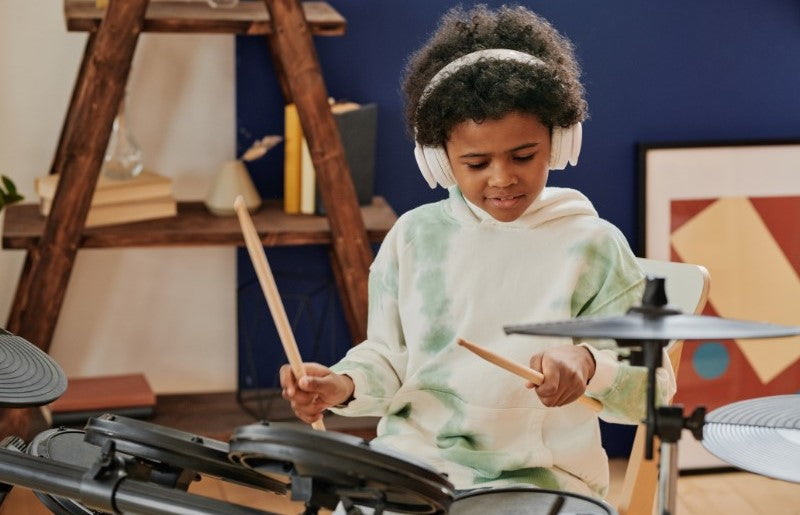 Boy playing drums wearing earmuffs