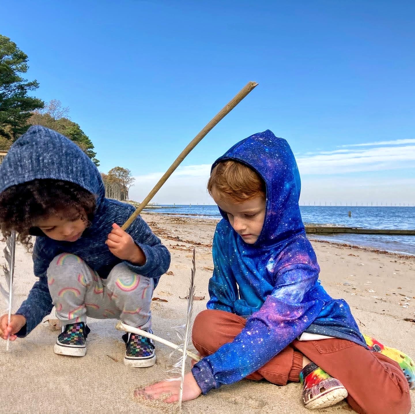two children playing with feathers in the sand