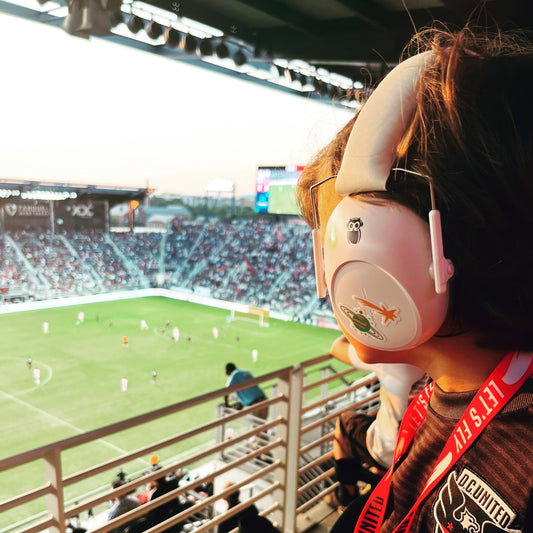 Boy wearing white hearing protection earmuffs at a professional soccer match