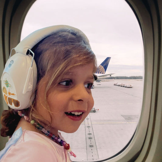 Girl sitting in an airplane with hearing protection on her ears